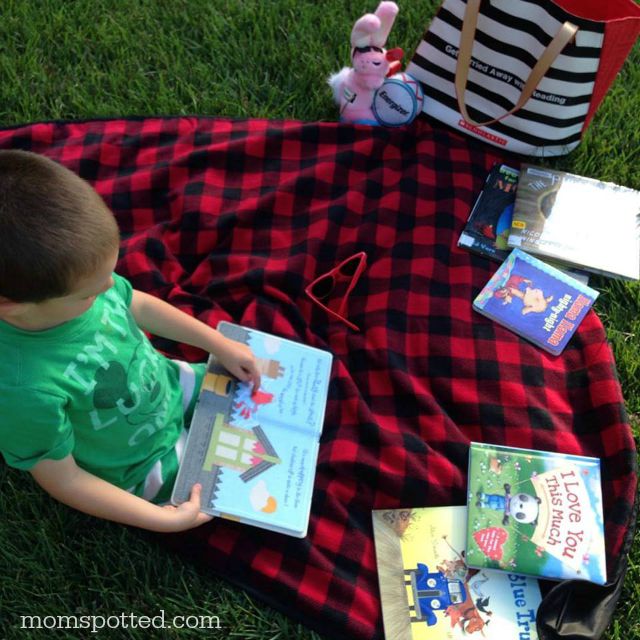 Sawyer reading his library books for his scholastic summer reading challenge